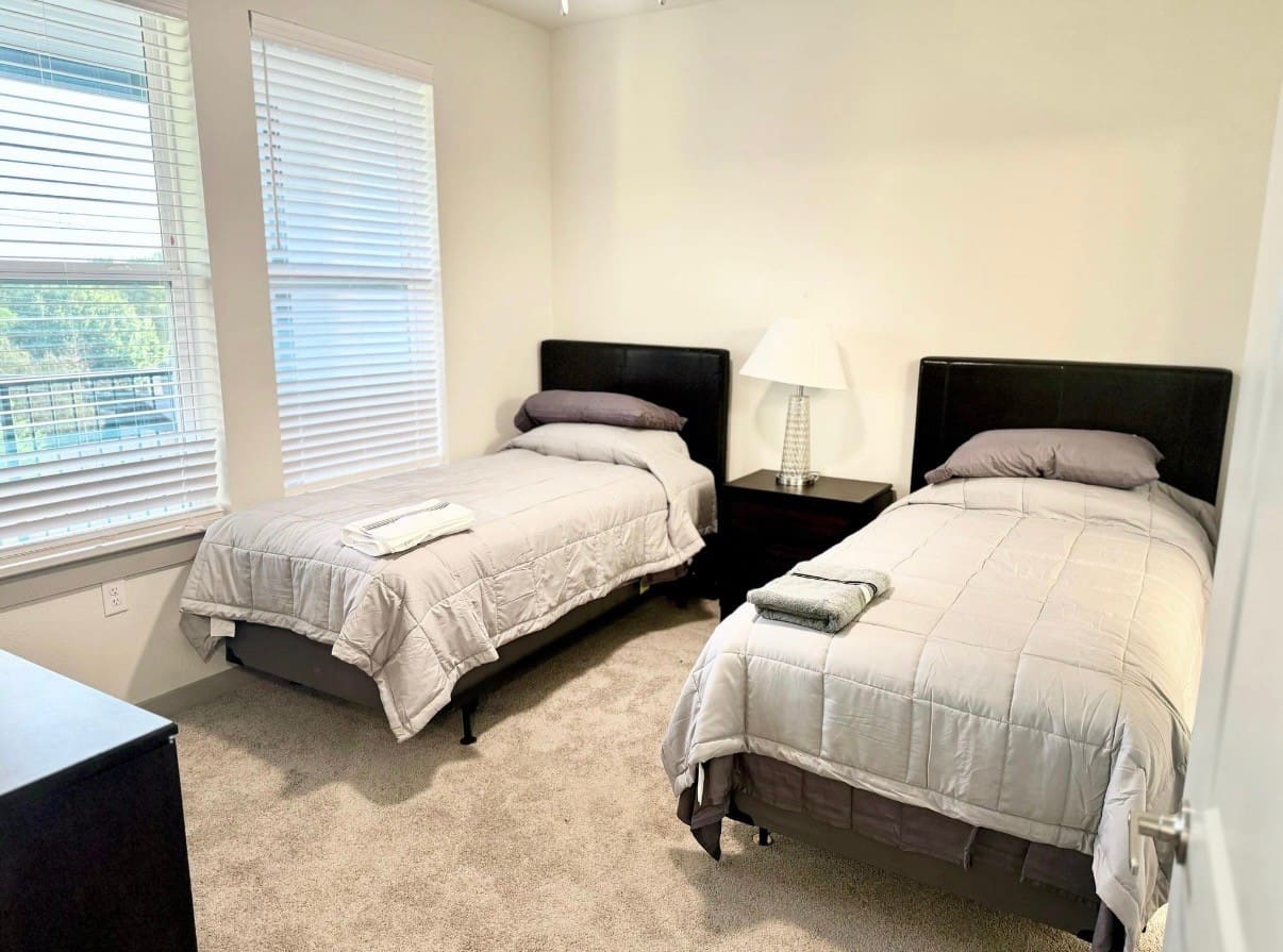 A bedroom with two beds and a nightstand.