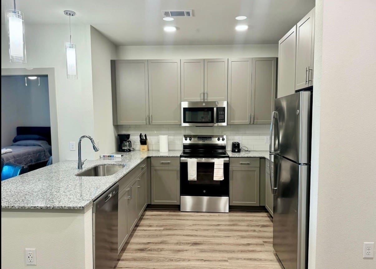 A kitchen with grey cabinets and stainless steel appliances.