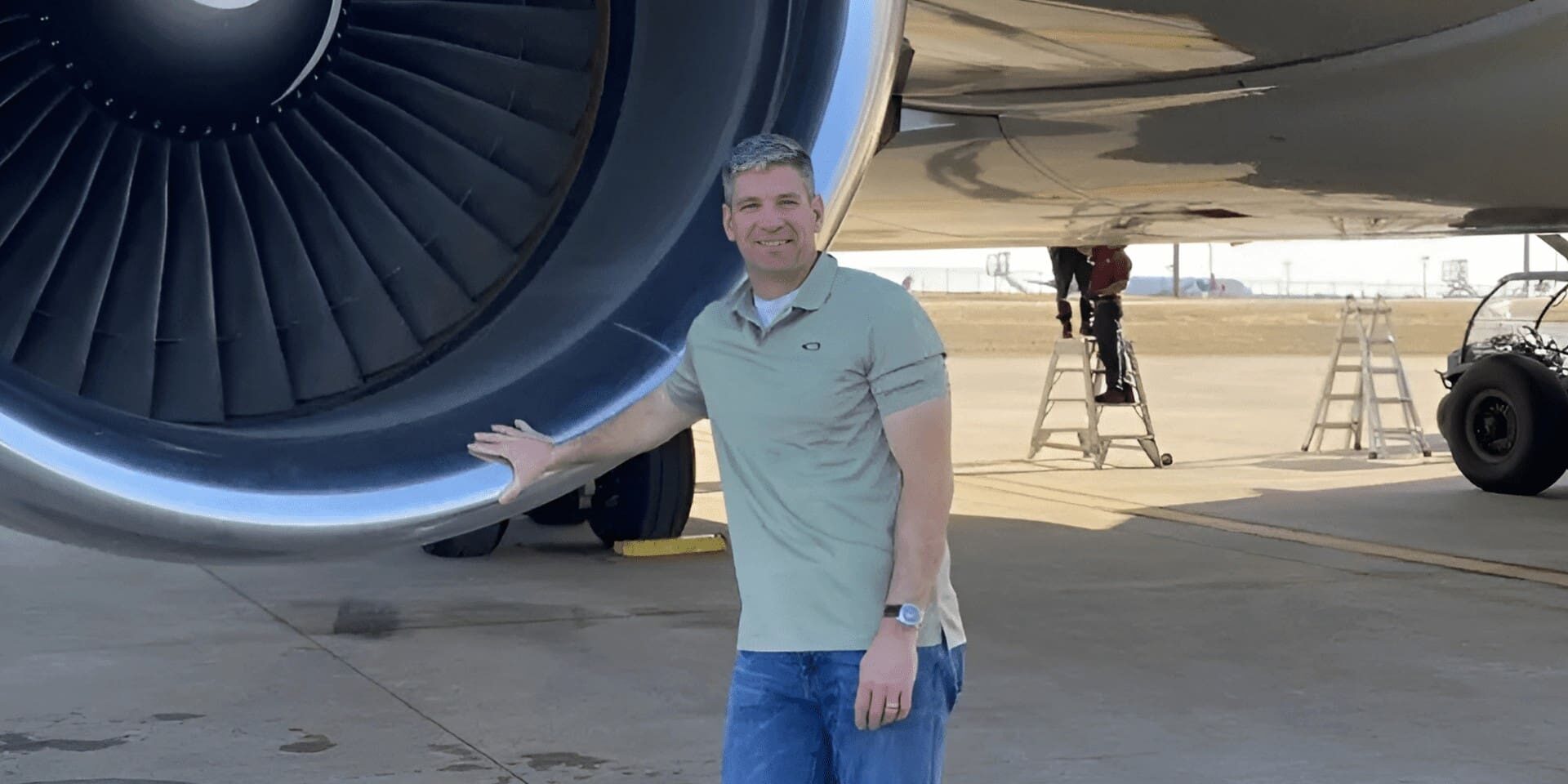 Man standing beside large airplane engine.