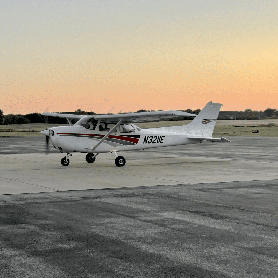 Small airplane on runway at sunset.